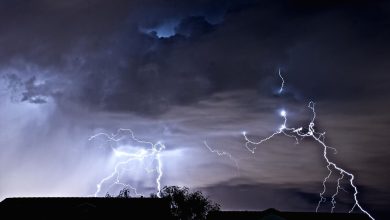 lightning bolts illuminating dark storm clouds at night