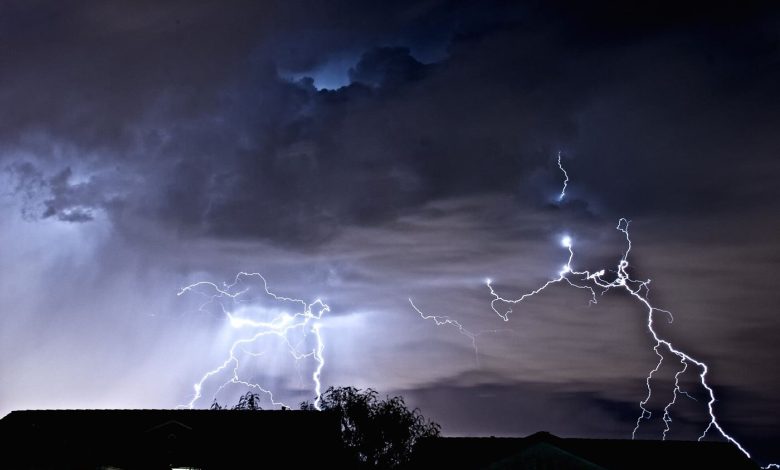 lightning bolts illuminating dark storm clouds at night