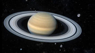 Saturn and its rings surrounded by many small moons in deep space